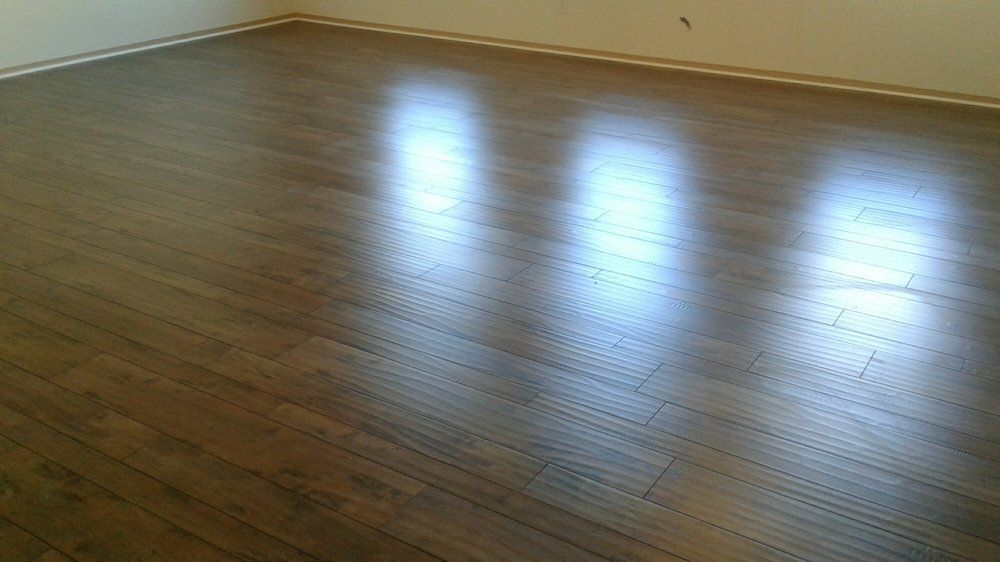 A polished dark brown hardwood floor reflects light, showing a smooth, clean surface in an empty room.