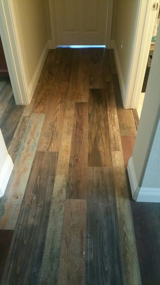 A hallway floor featuring wood-look vinyl planks with varying light, medium, and dark brown tones.