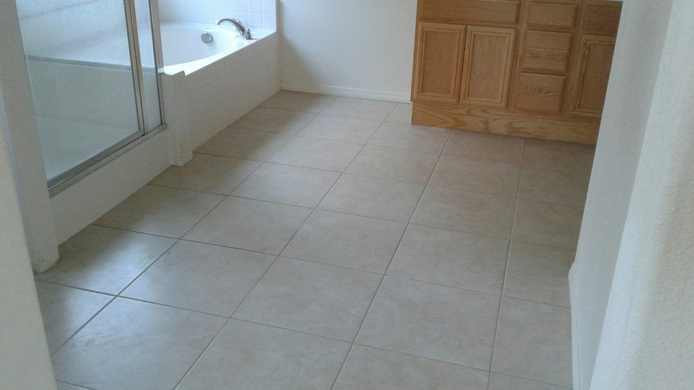 A bathroom with light-colored tile flooring, a glass-enclosed shower, a corner bathtub, and a wooden vanity cabinet.