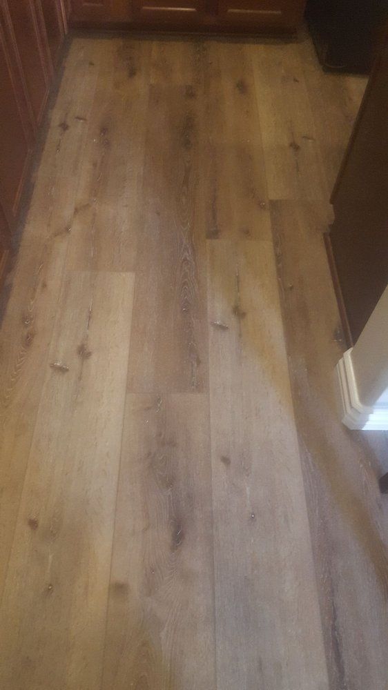 A perspective view of light brown, wood-textured vinyl or laminate plank flooring in a kitchen setting.