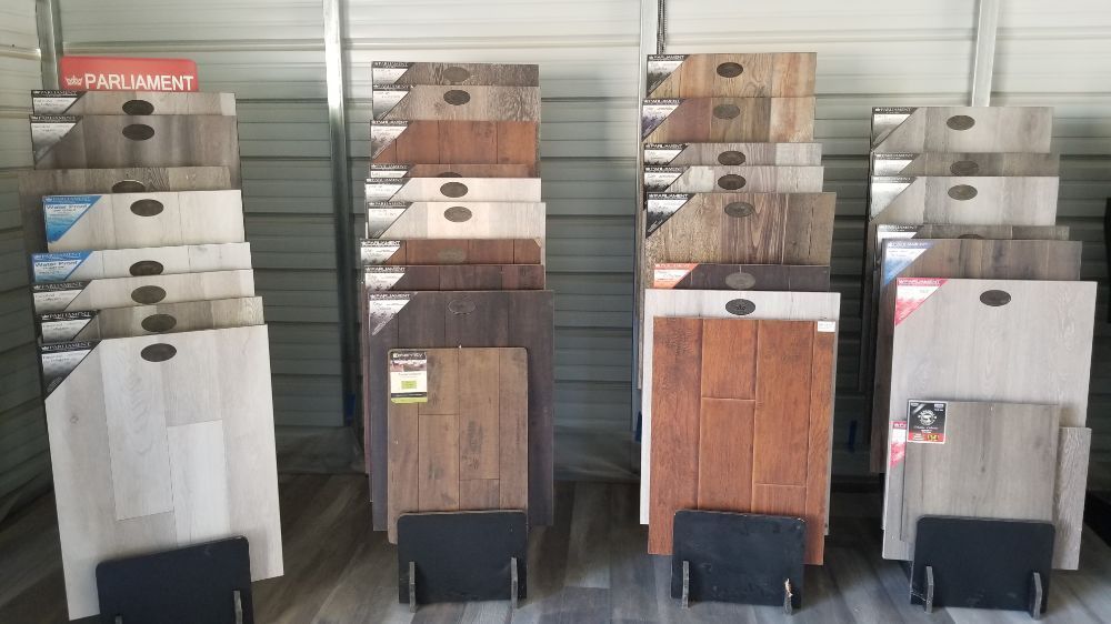 Four display racks showcasing various wood-look laminate or vinyl flooring samples in a store.