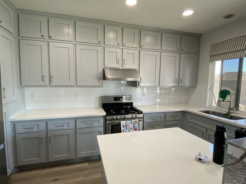 Modern kitchen with gray cabinets, white countertops, subway tile backsplash, and a central island.