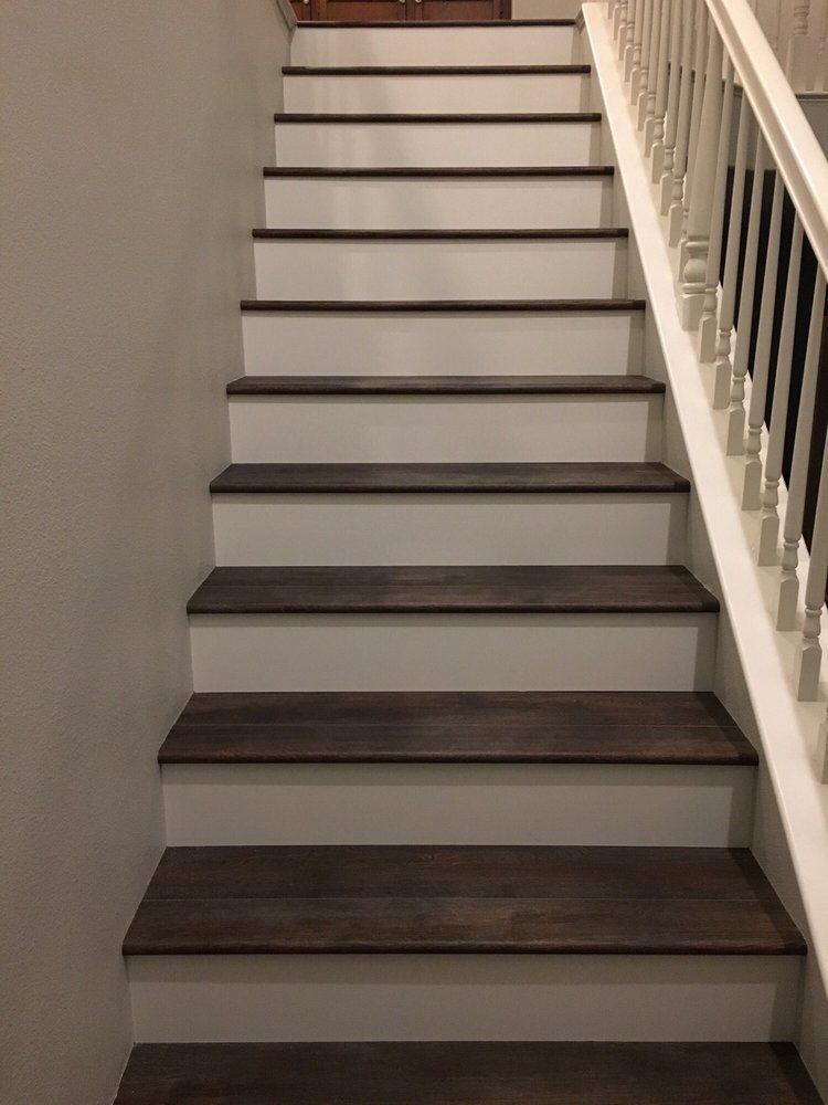 Staircase with dark wooden treads and white risers, featuring a white railing on the right side.