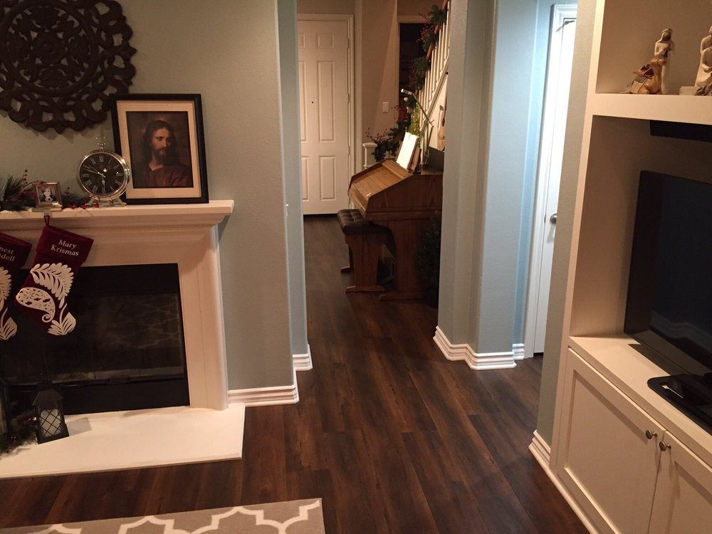 A living room interior featuring a fireplace with stockings, a wood-toned piano in a hallway, and built-in cabinetry.