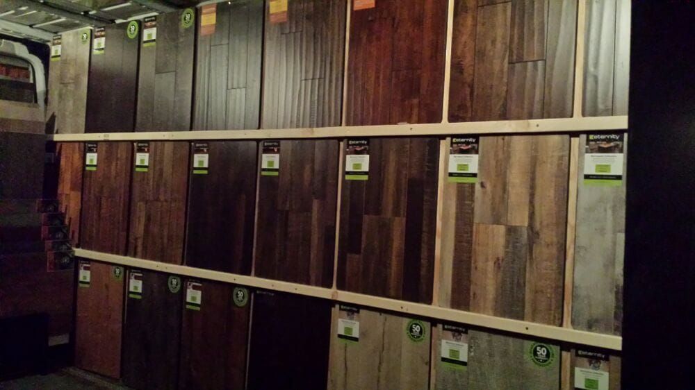 A display rack featuring rows of various wood flooring samples in different shades and textures.