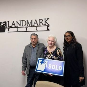 People at Landmark Title celebrate a home sale, holding a 