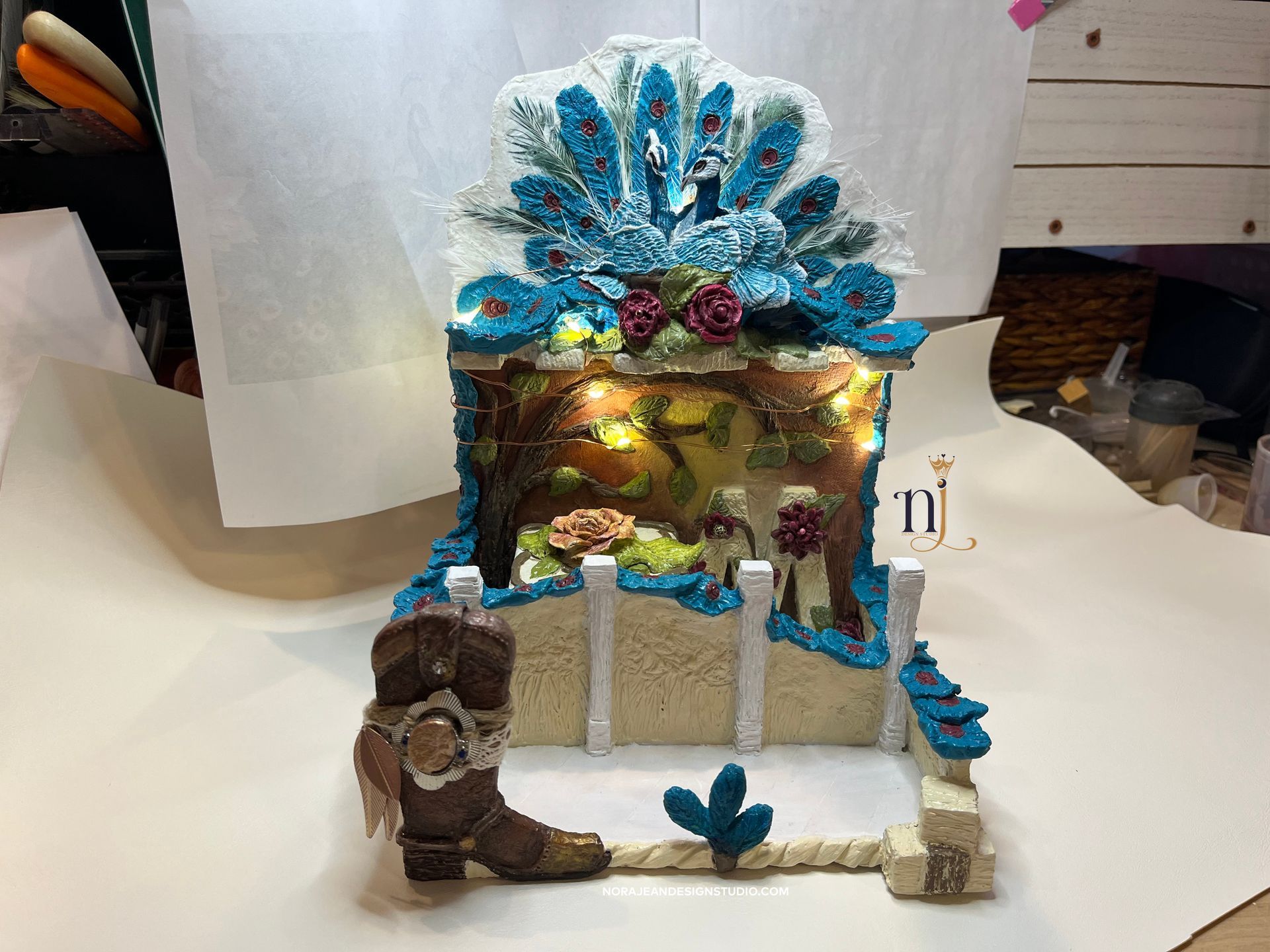 A diy bedside cell phone docking station peacock theme with a cowboy boot on a table.