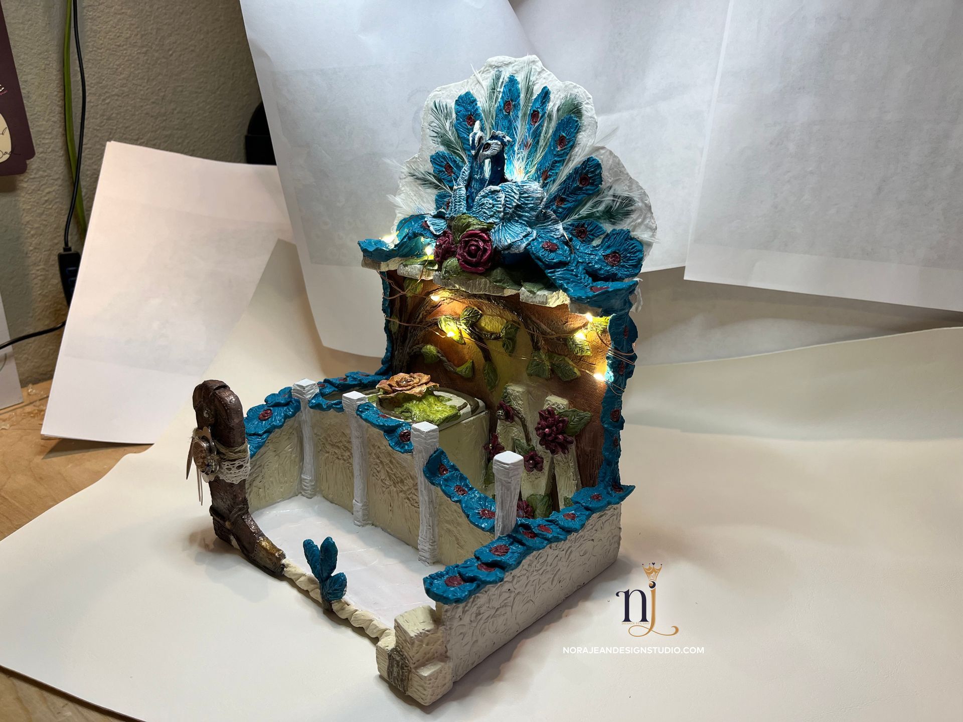 A diy bedside cell phone docking station peacock theme with a cowboy boot on a table.