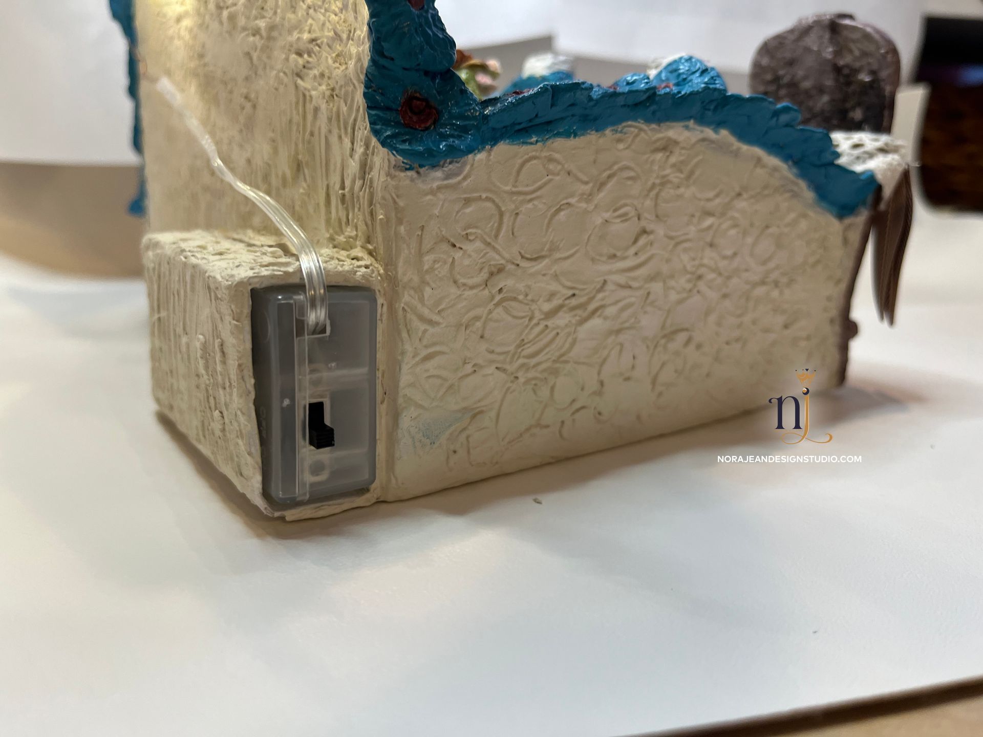 A diy bedside cell phone docking station peacock theme with a cowboy boot on a table.