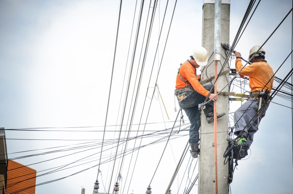 Two Utility Workers Climb a Concrete Pole to Perform Electrical Maintenance — Macleay Energy Solutions In Kempsey, NSW