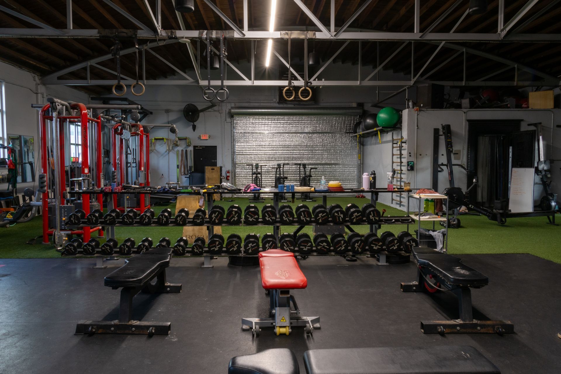 A gym filled with lots of dumbbells and benches.