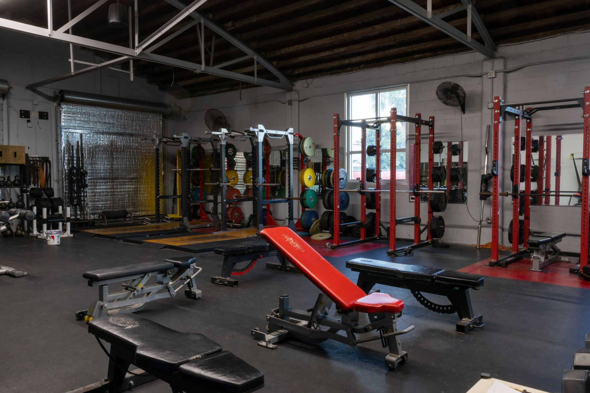 A gym filled with lots of exercise equipment and benches.