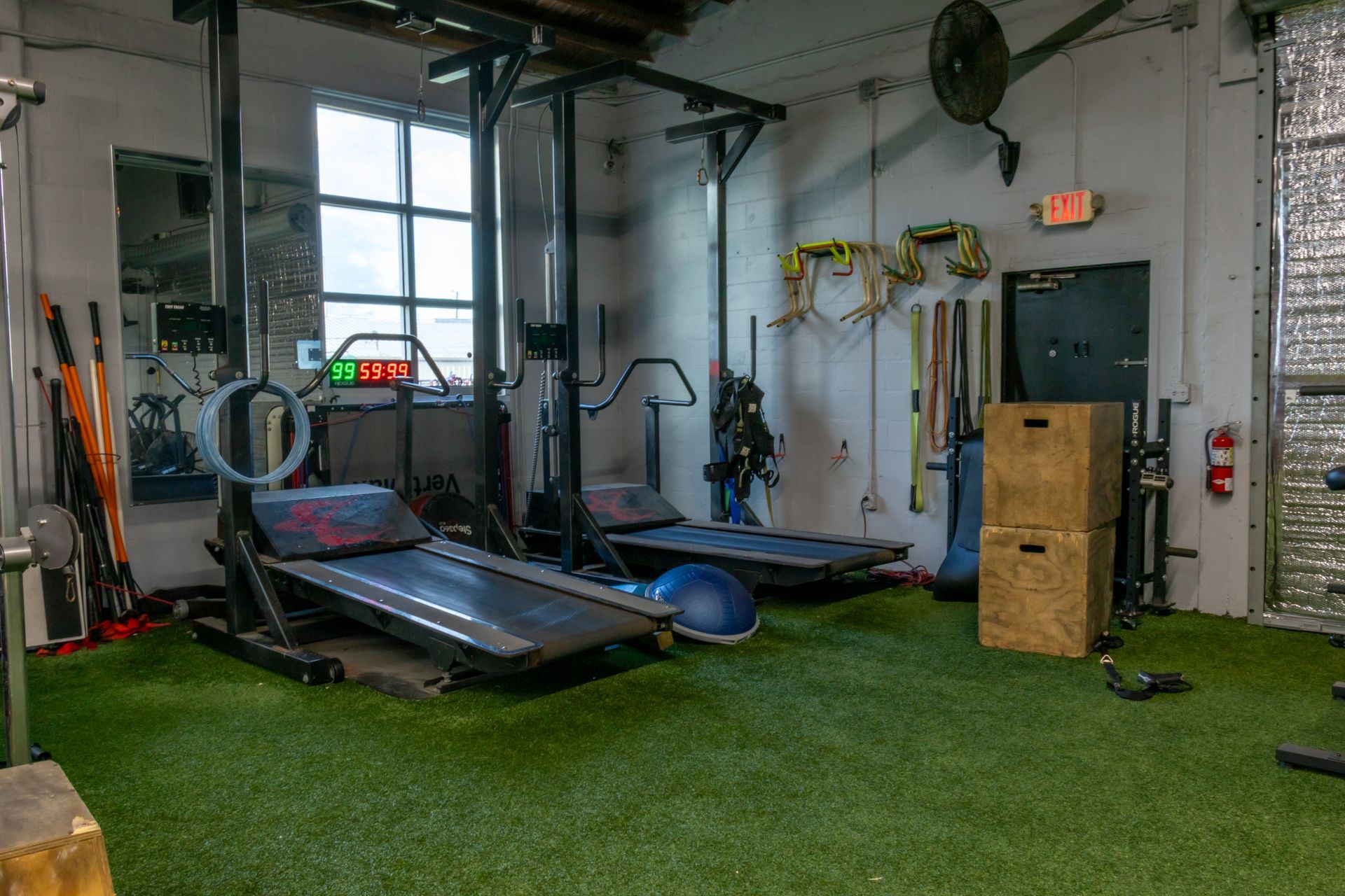 There are two treadmills in the gym with a lot of equipment.