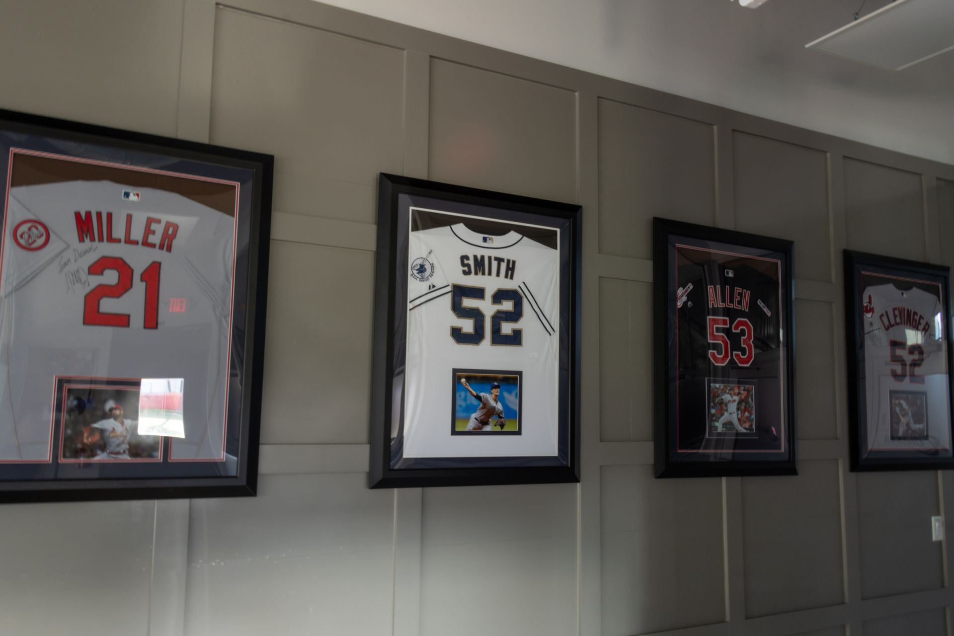 Four framed baseball jerseys are hanging on a wall.