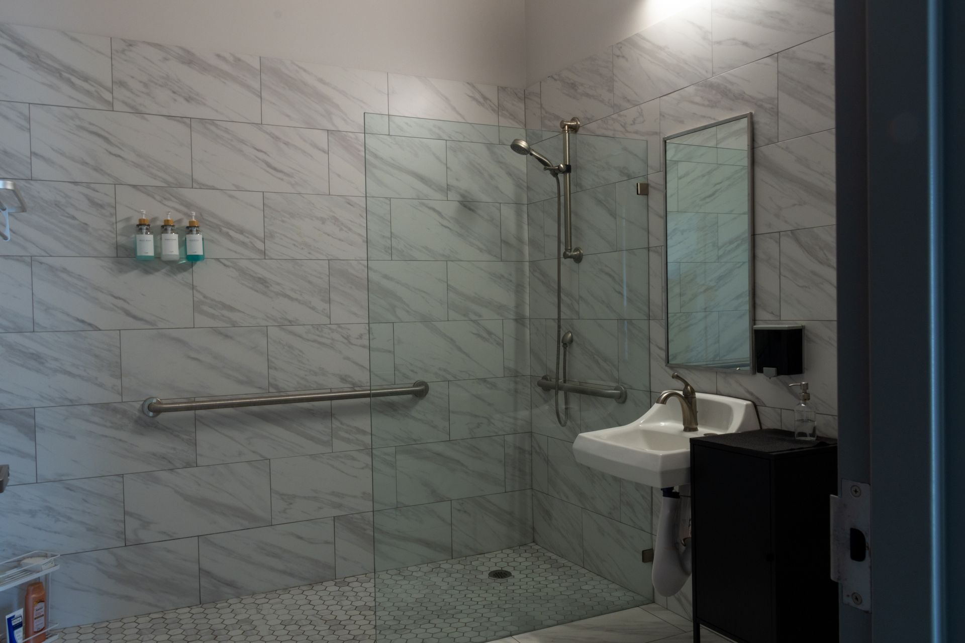 A bathroom with a walk in shower , sink and mirror.