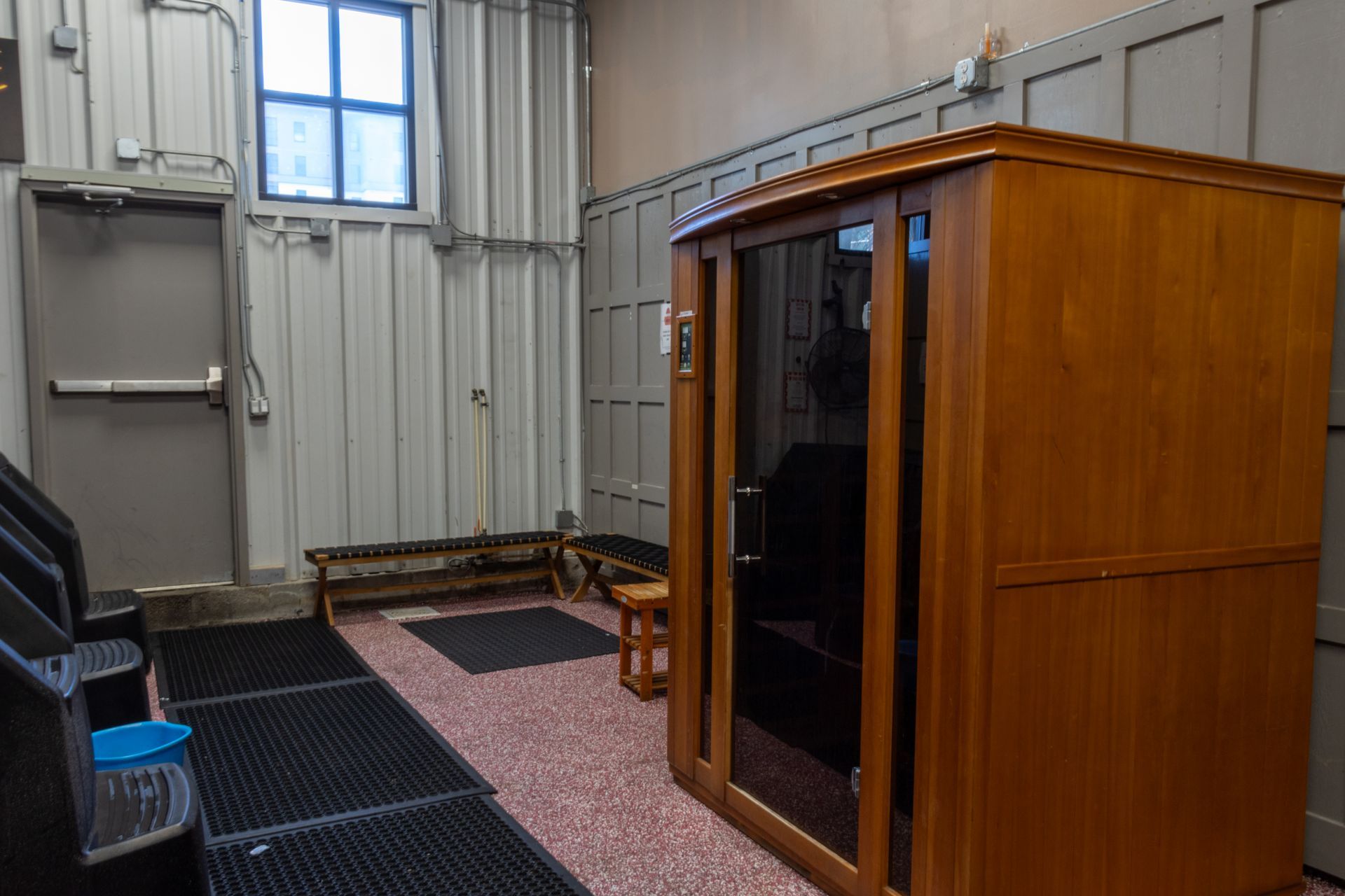 A wooden sauna is sitting in a room next to a window.