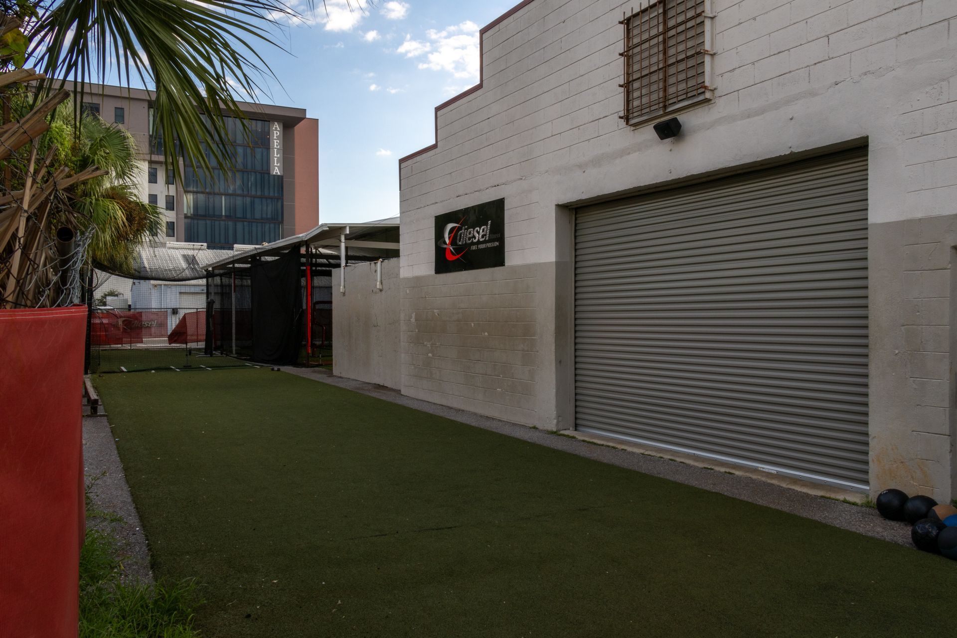 A white building with a gray garage door and a red potted plant in front of it.