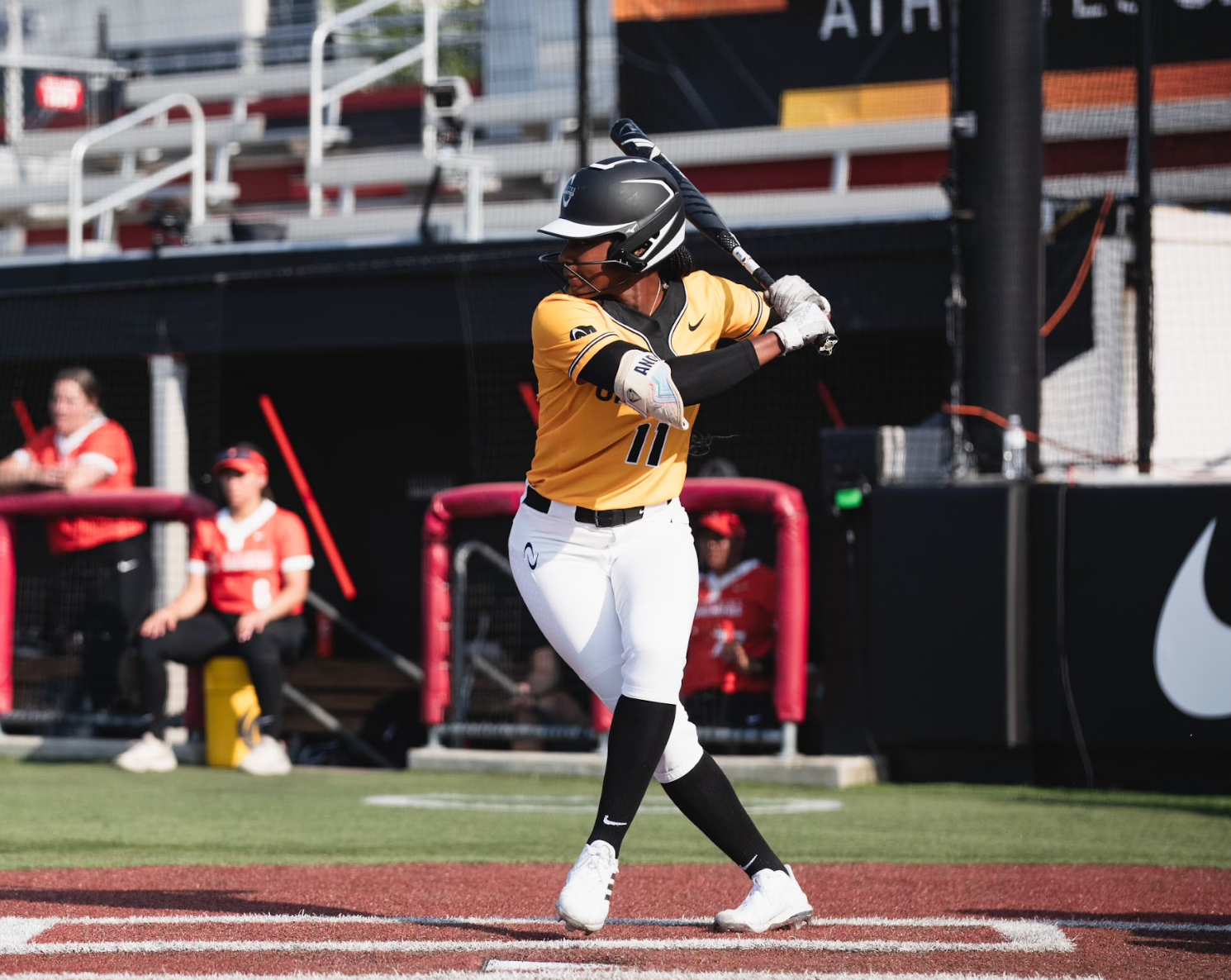 A young girl practices softball batting with a coach. They are in an indoor practice setting.