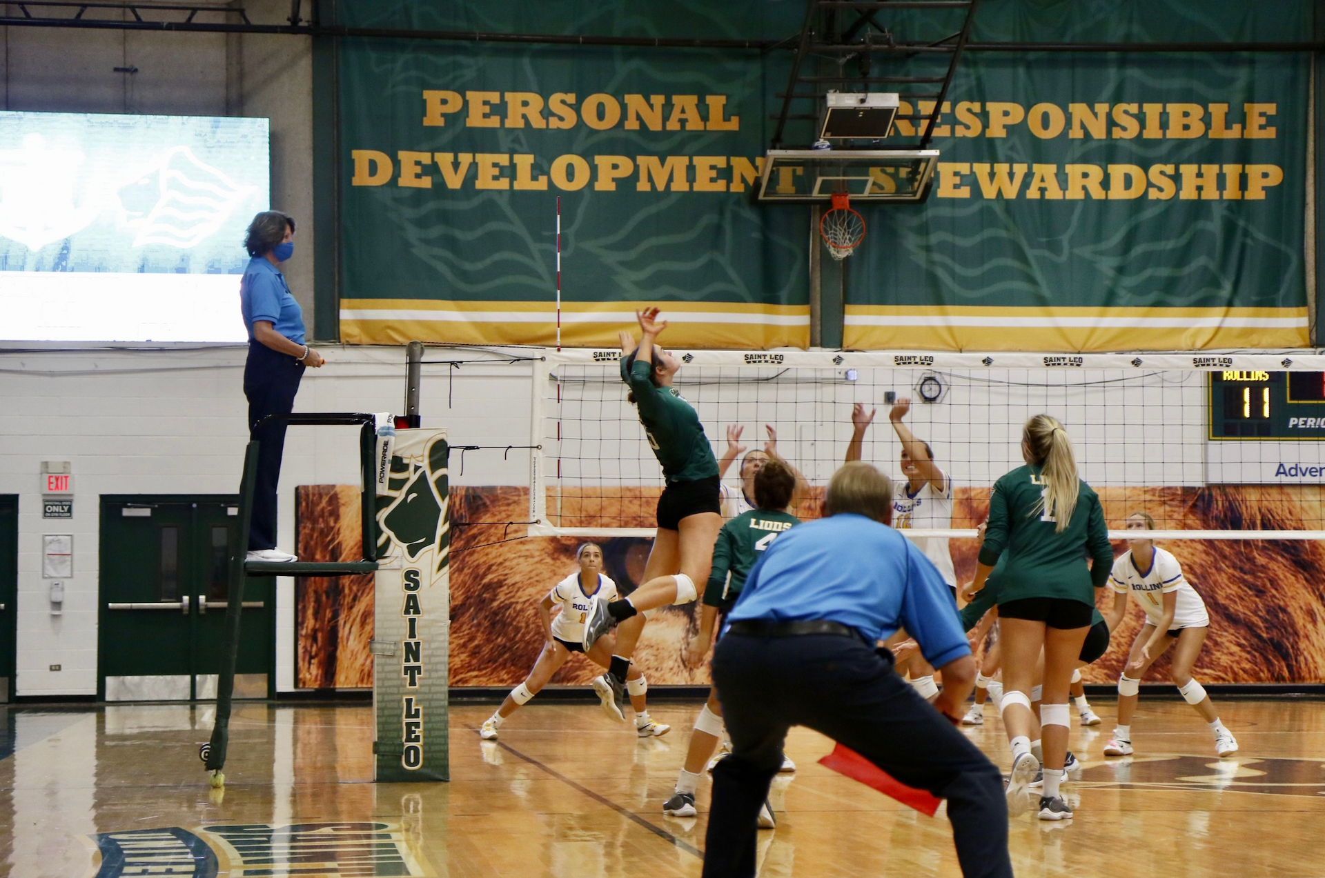 Softball pitcher in maroon jersey, white pants, and black cleats throwing a yellow ball on a dirt field.