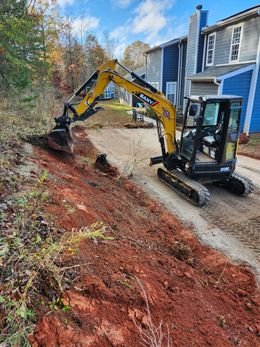 A yellow excavator is digging a hole in the dirt in front of a house.