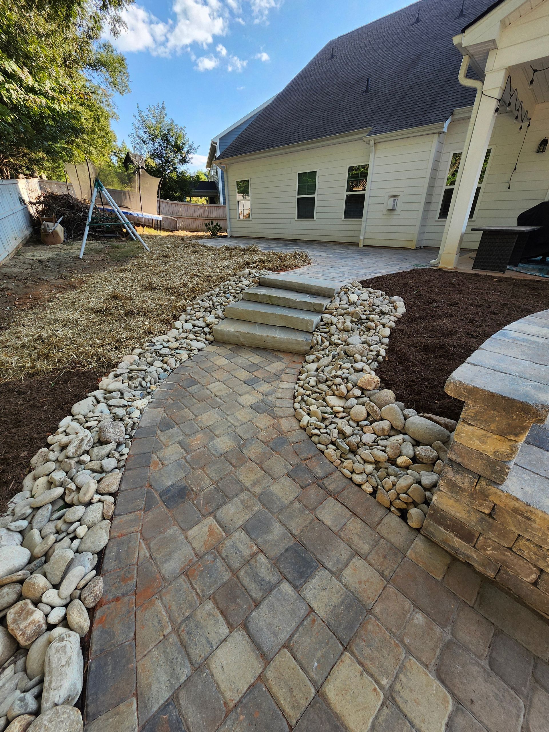 A sidewalk made of bricks is being built in a yard.
