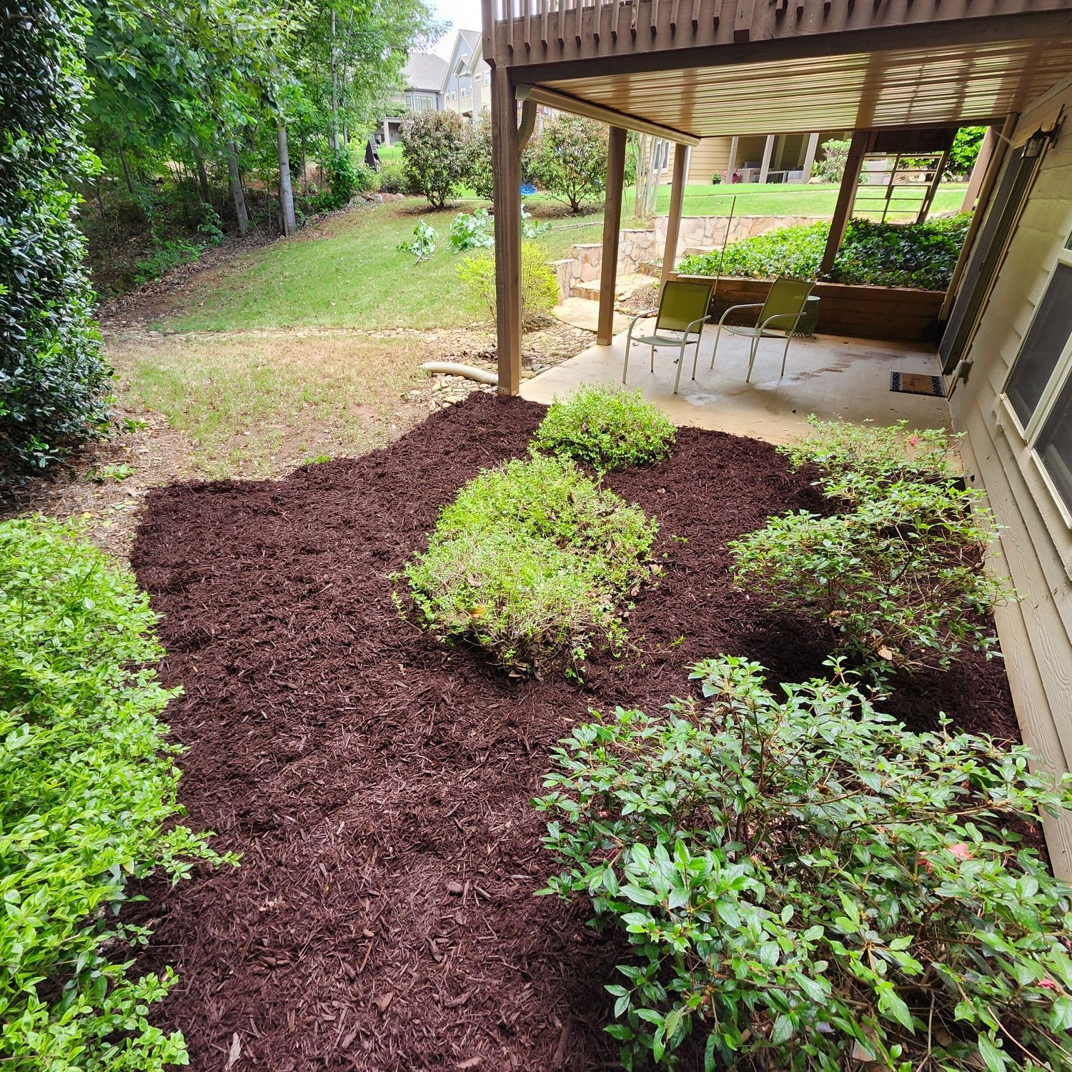 A backyard with a deck and a lot of mulch.