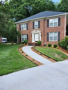 A large brick house with a concrete driveway leading to it.