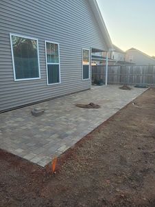 A patio is being built in the backyard of a house.