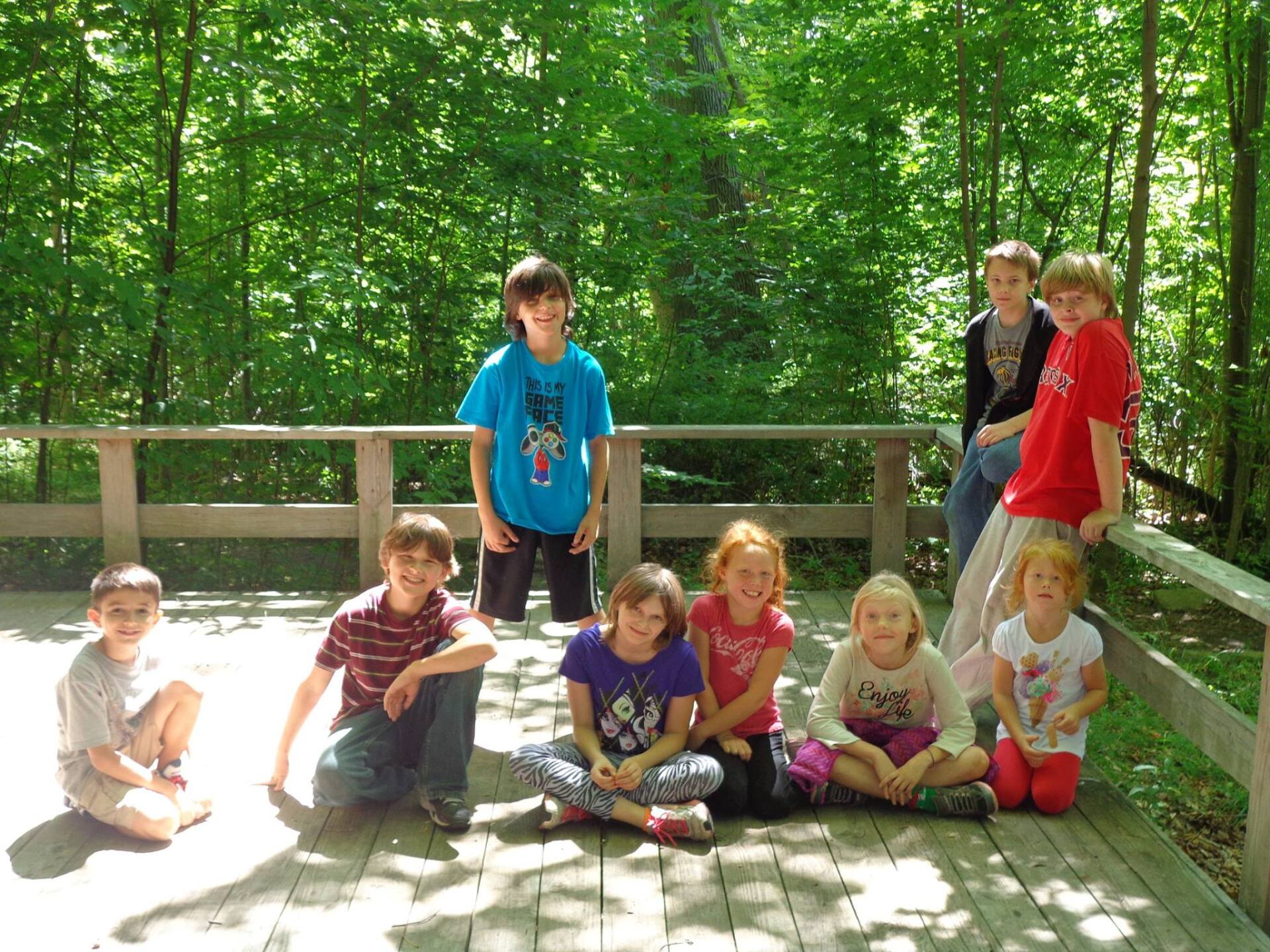 A group of children are posing for a picture on a wooden deck