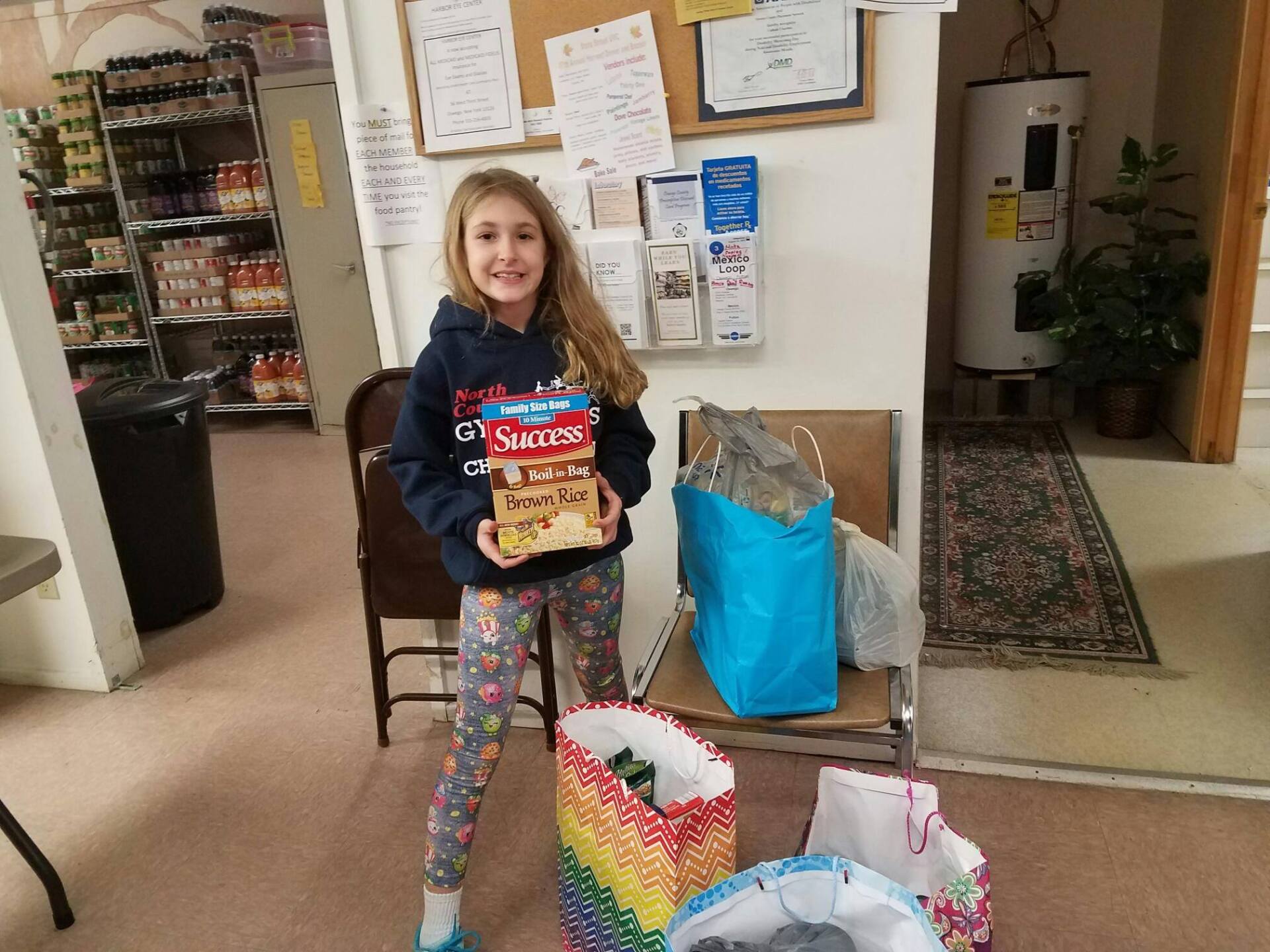 A little girl is holding a bag of skittles