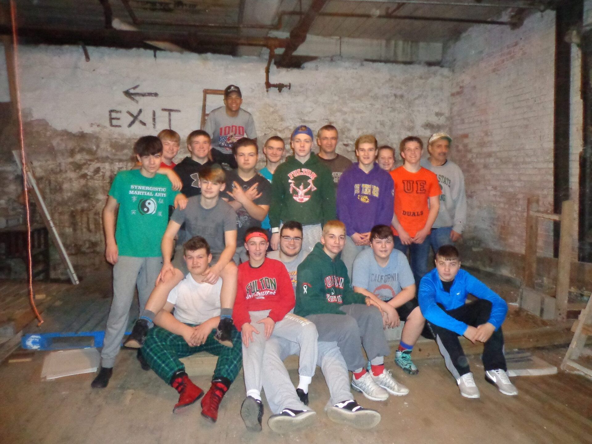 A group of young men pose for a picture in front of an exit sign