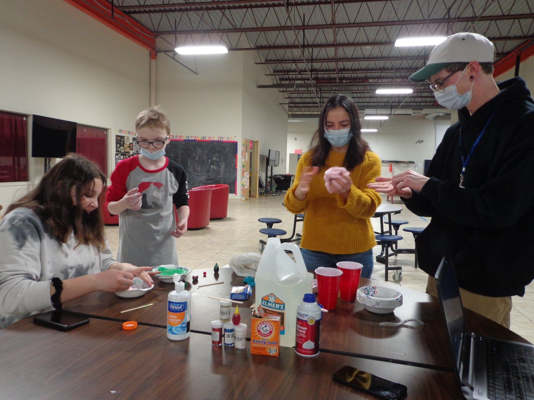 A group of people are standing around a table with various items on it.