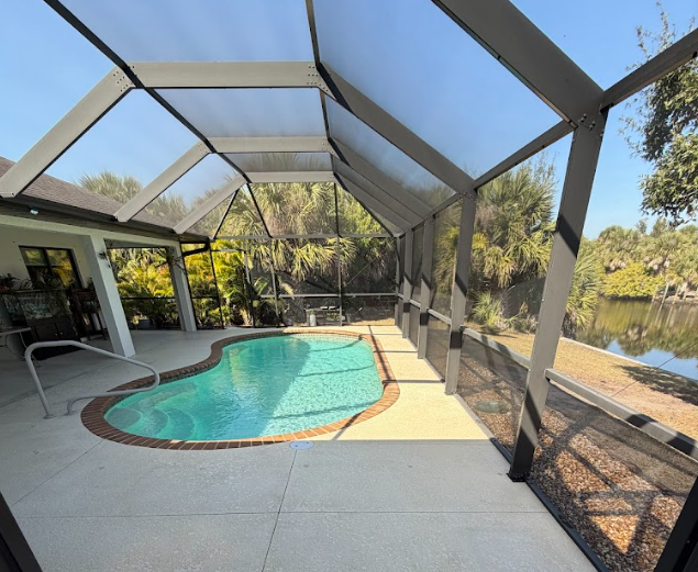 Driveway leading to a large light blue house with lush landscaping and trees.