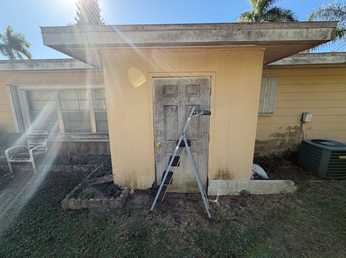 Aerial view of a driveway with a car, surrounded by green lawns and tropical landscaping.