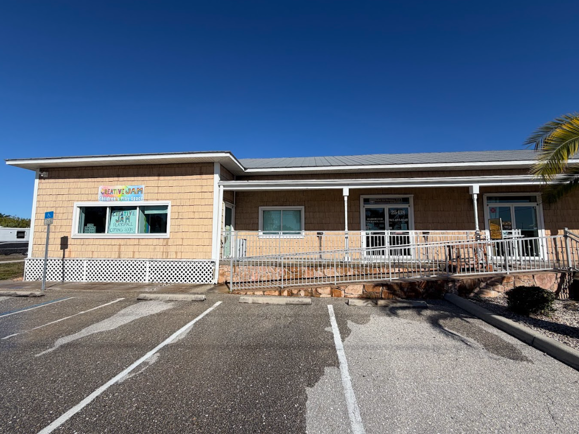 Building exterior with accessible ramp and parking, under a clear blue sky.