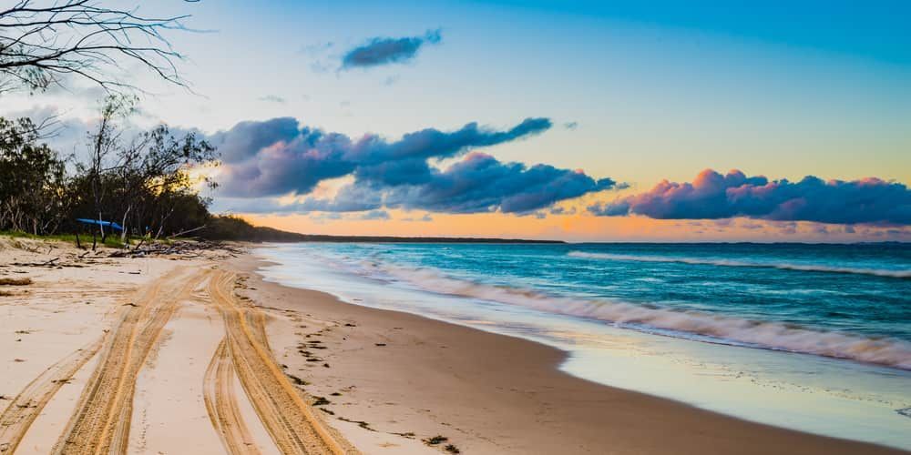 Sandy Beach with Tire Tracks, Ocean, and Cloudy Sky at Sunset — Tomac Civil In Brisbane, QLD