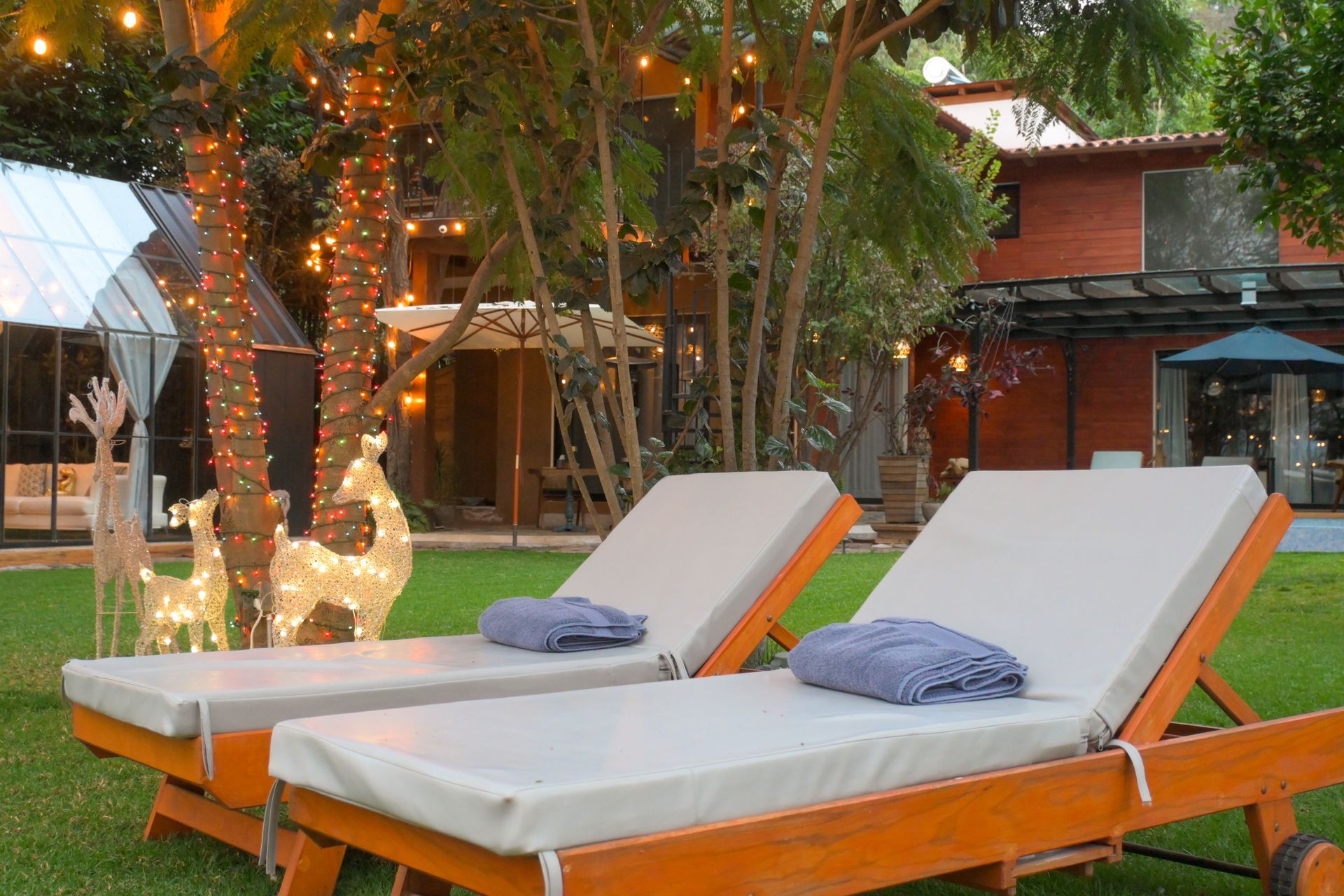 Dos sillones están sentados en el césped frente a una casa.