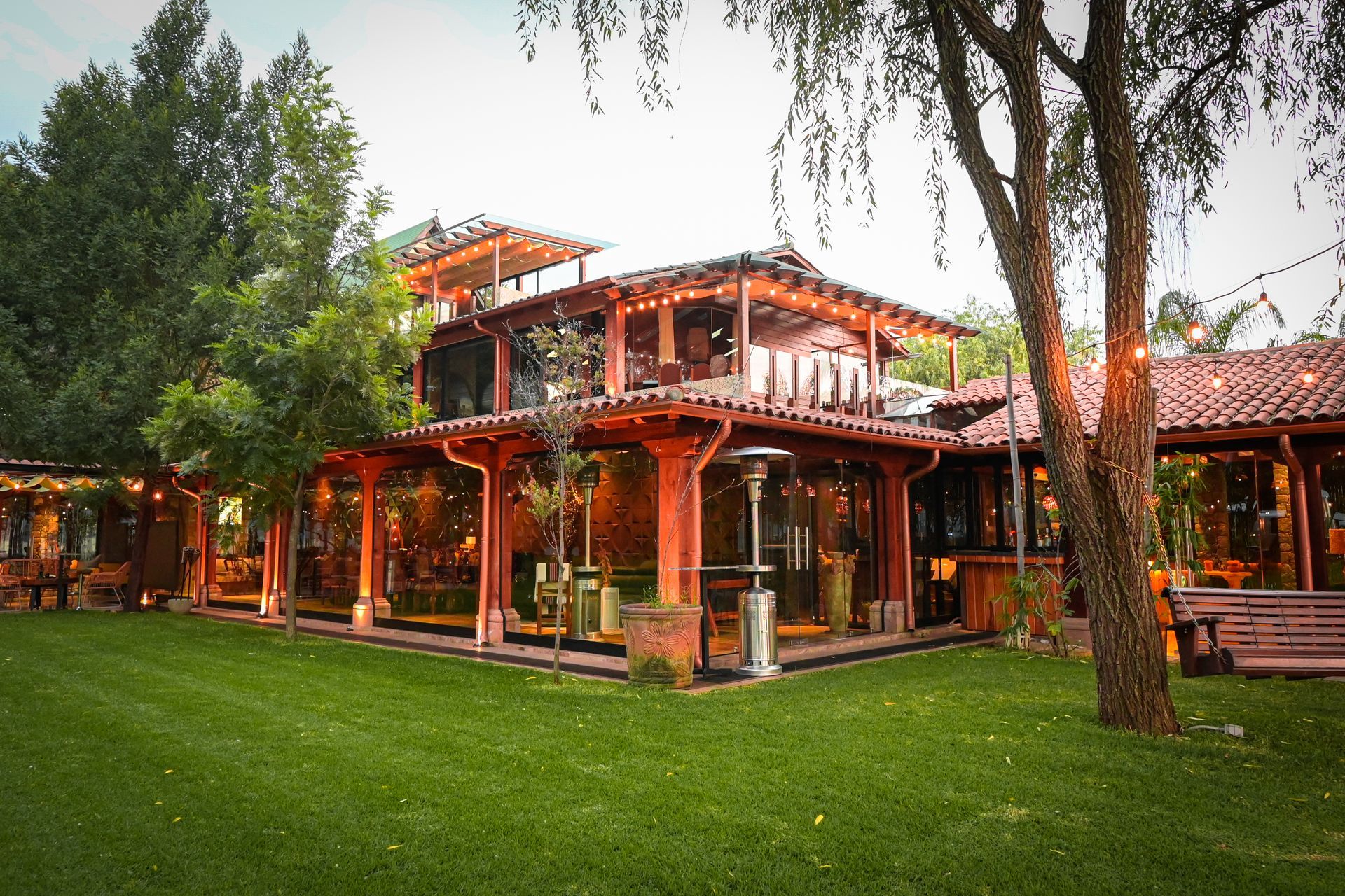 Una casa grande con muchas ventanas está rodeada de árboles.