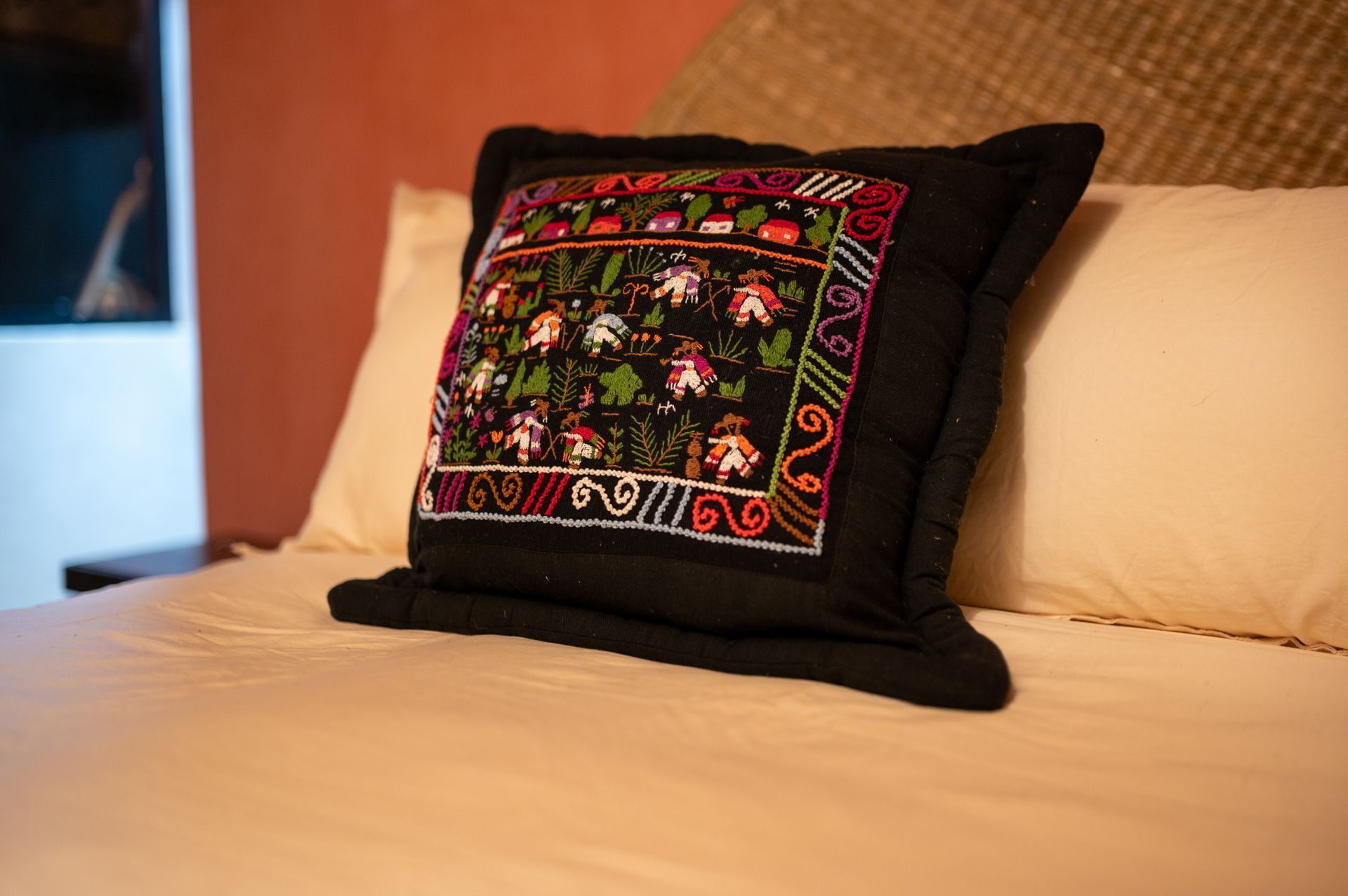 Una almohada negra con un estampado floral está sobre una cama.