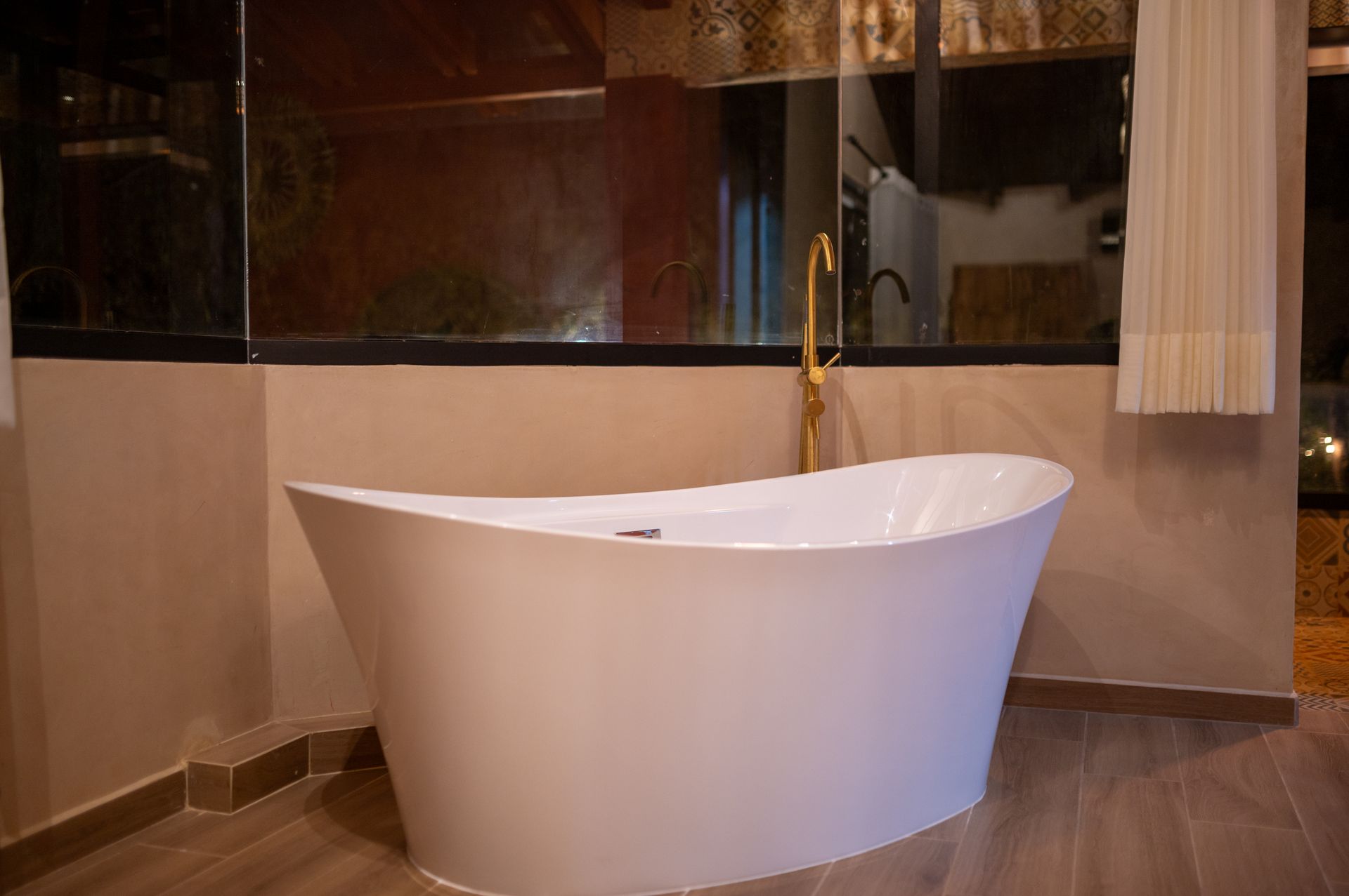 Una bañera blanca está situada en un baño al lado de una ventana.