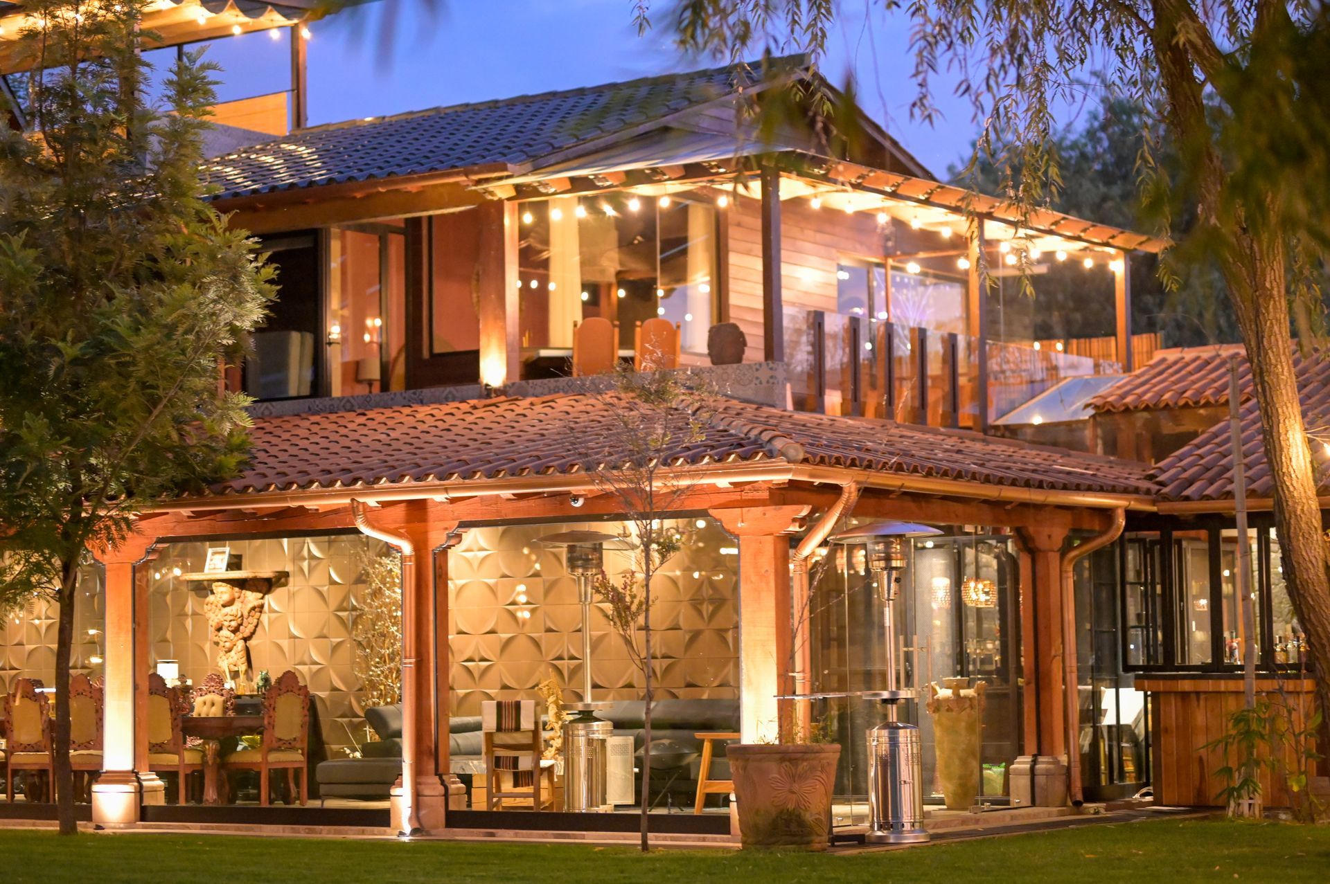 Una casa grande con muchas ventanas está iluminada por la noche.