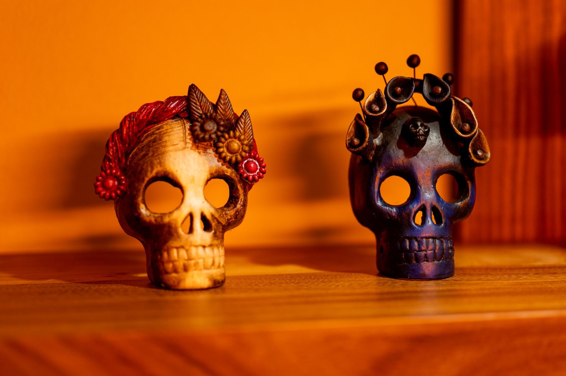 Dos calaveras de azúcar están sentadas sobre una mesa de madera.