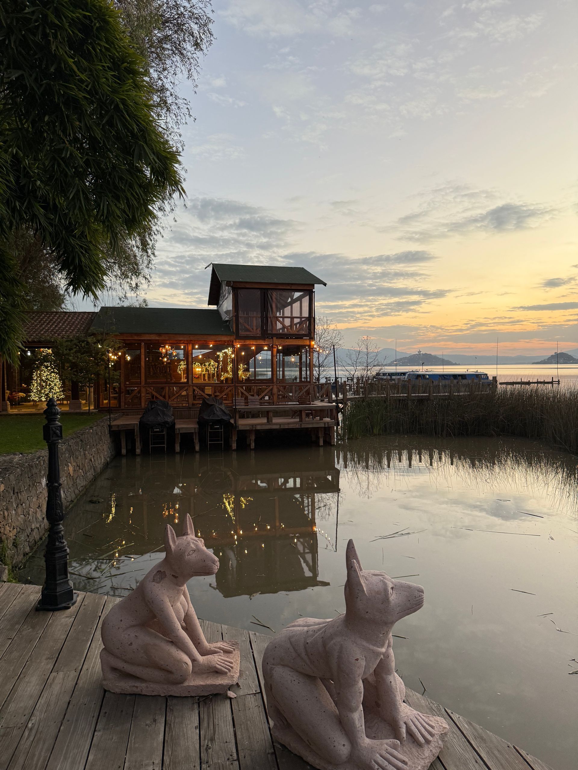 A couple of statues sitting on a dock next to a body of water.