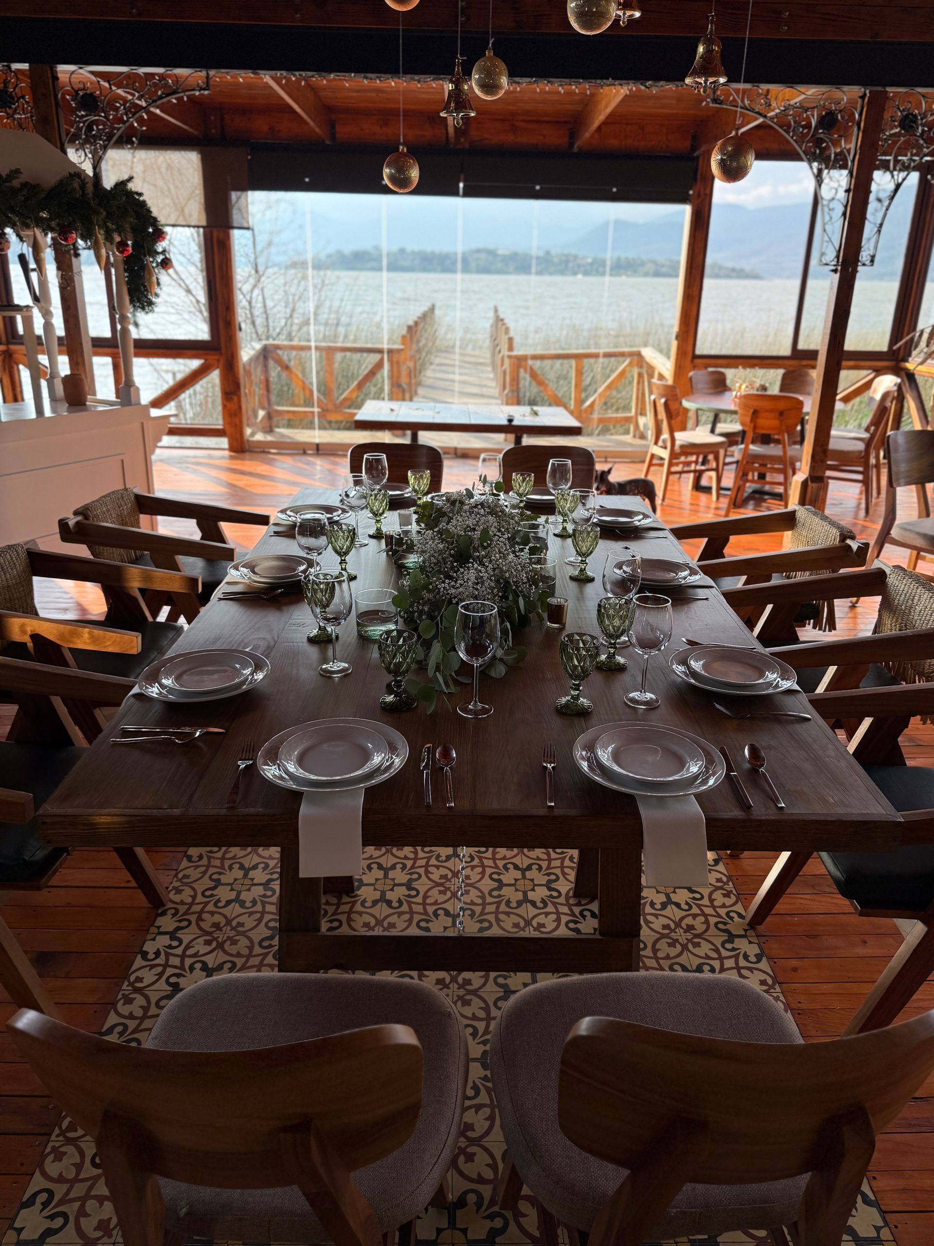 Una mesa de comedor con platos, vasos y flores sobre ella.