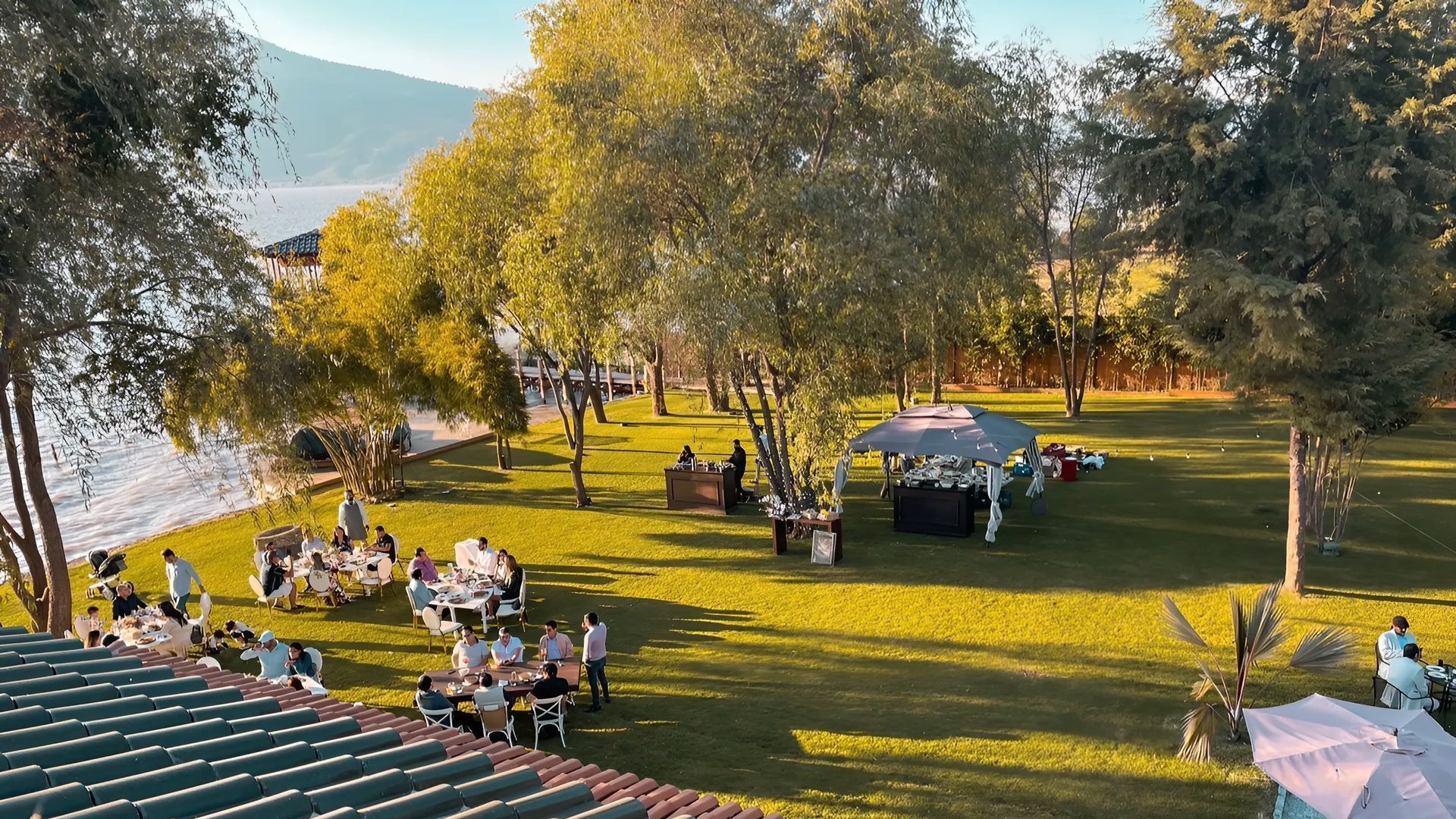 Un grupo de personas están sentadas en mesas en un parque.
