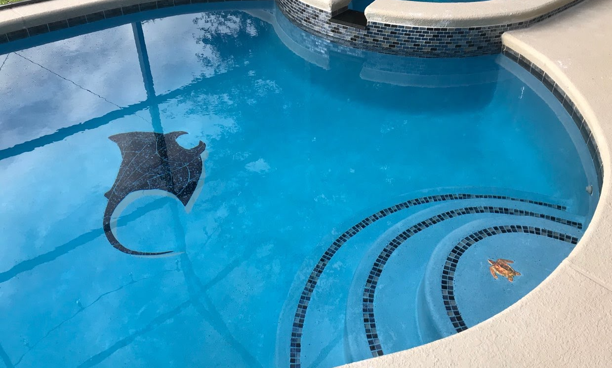 Pool with blue water and a stingray mosaic on the bottom.