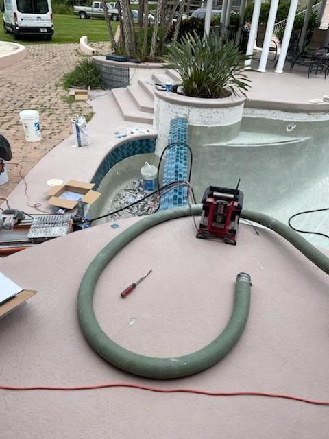 Pool under construction with a hose and equipment.