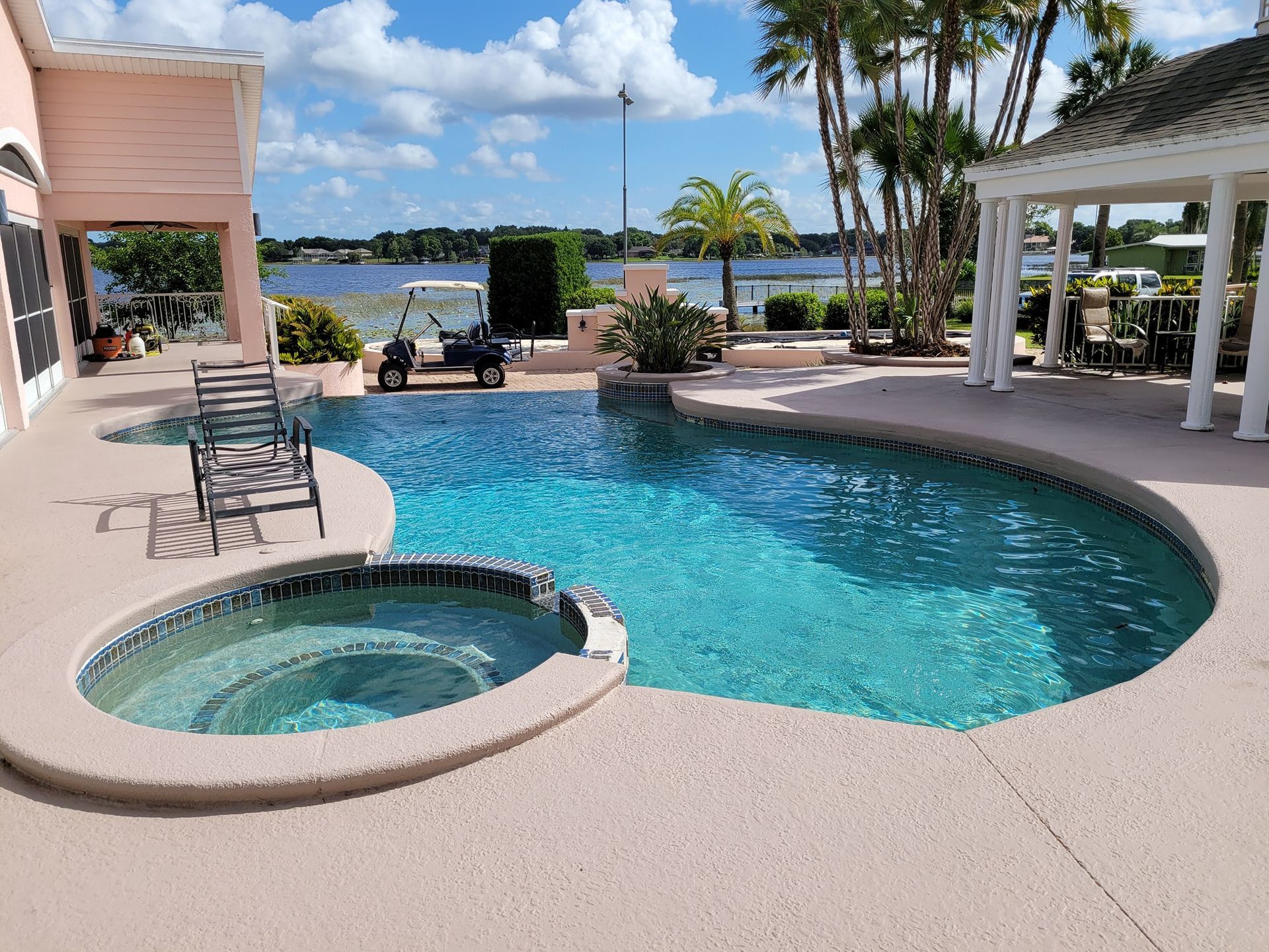 Swimming pool with a connected jacuzzi, a golf cart, and a lake view.