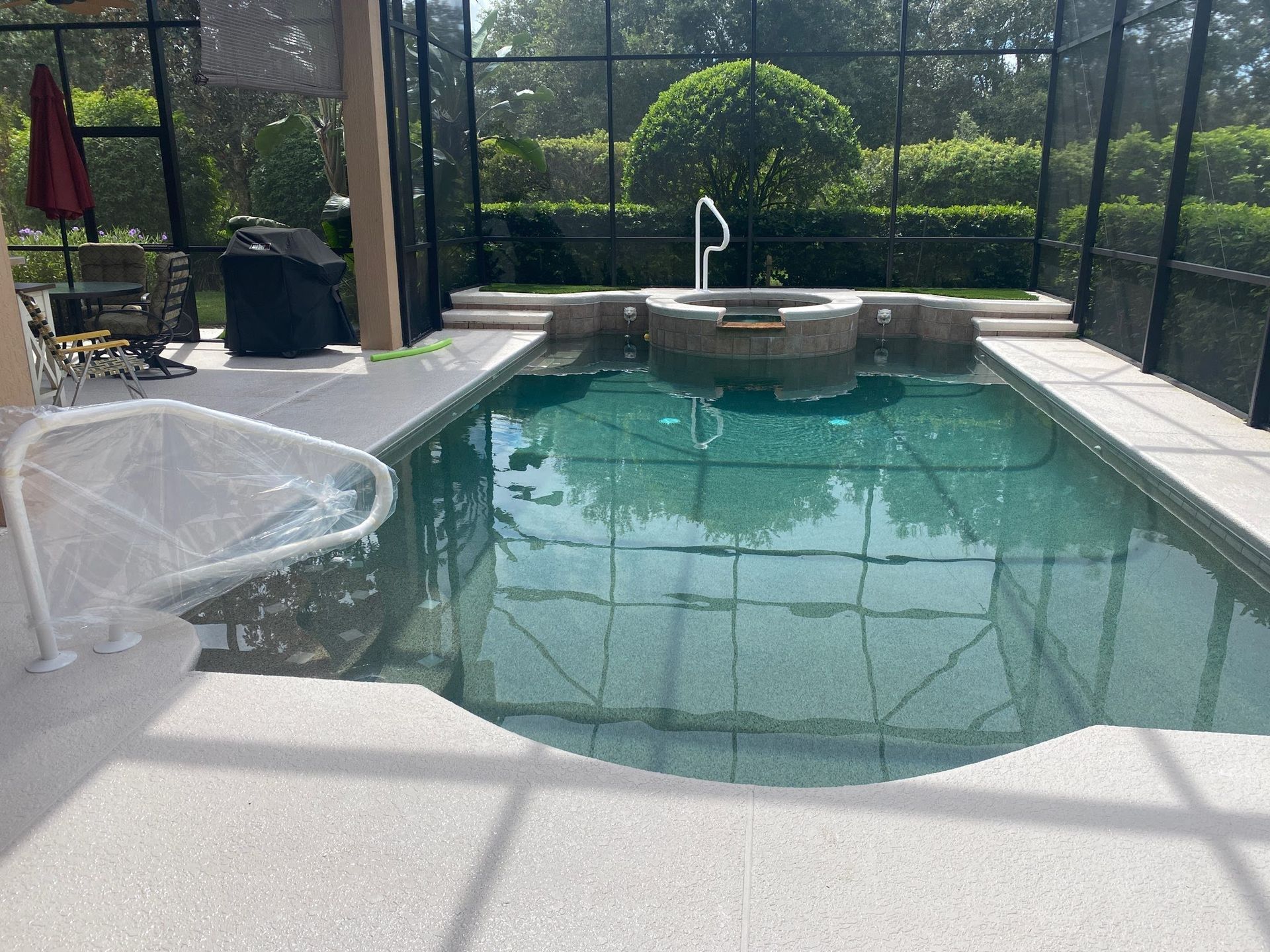 A large swimming pool is surrounded by a screened in area