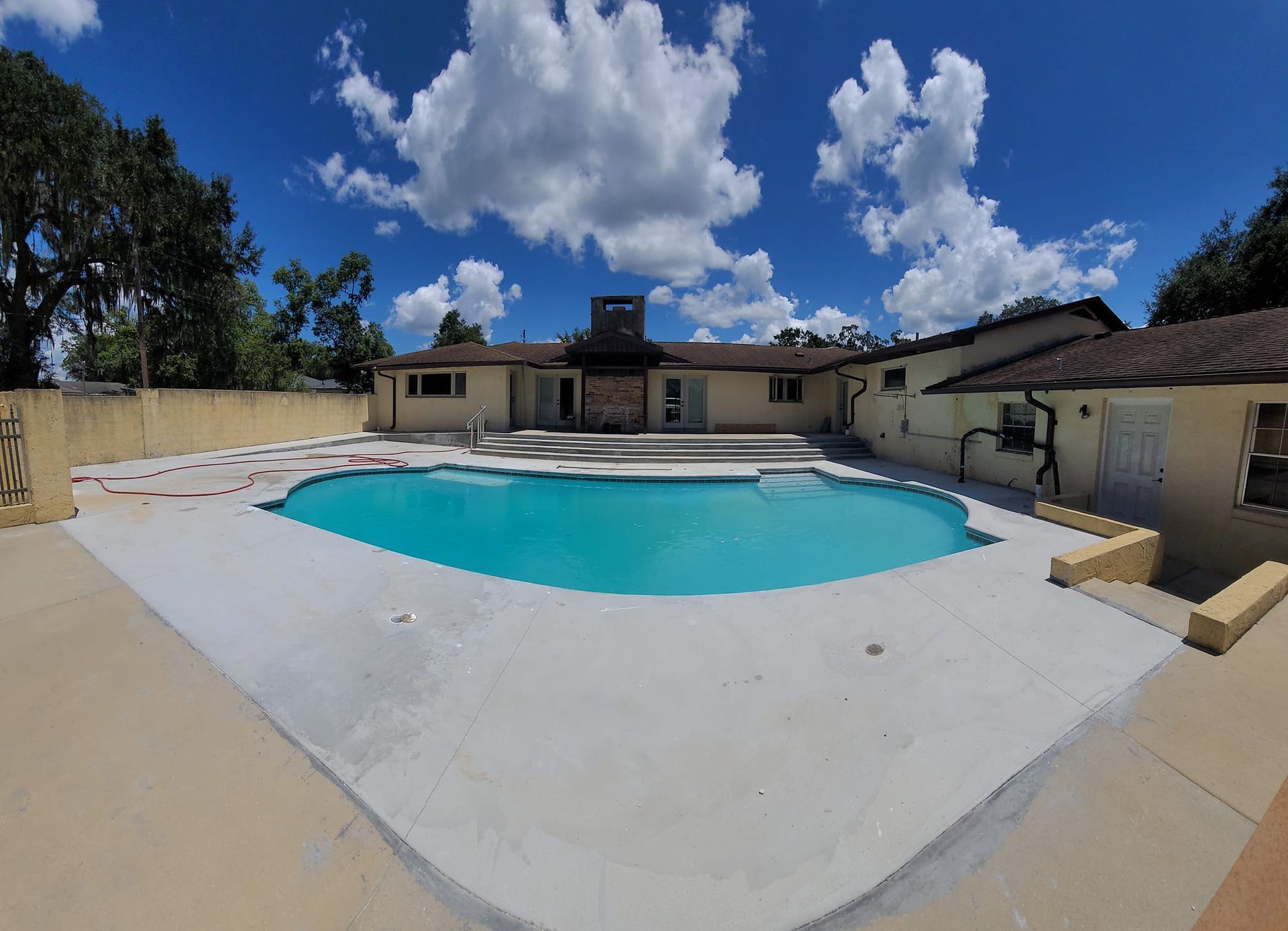 A large swimming pool in front of a house on a sunny day
